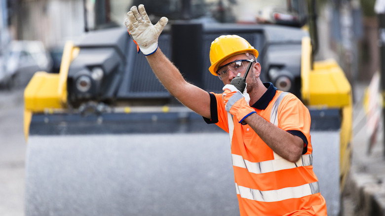 Worker in orange hard hat on road work site