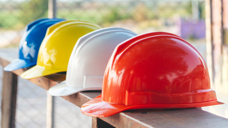 Hard hats lined up on a wooden fence