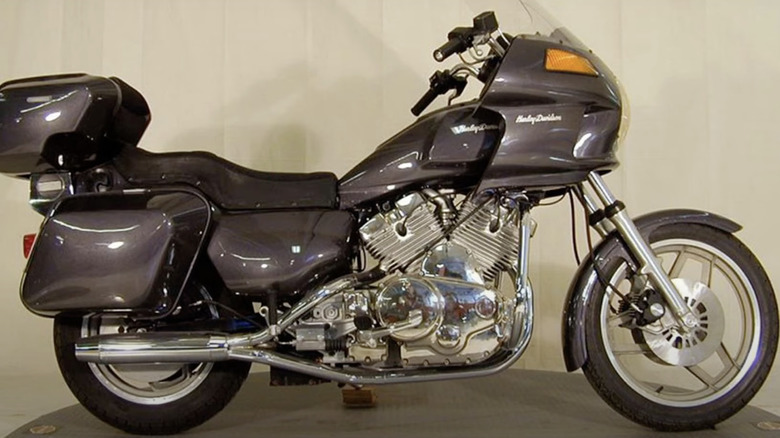 Grey Harley-Davidson Nova motorcycle on small round platform in front of tan wall