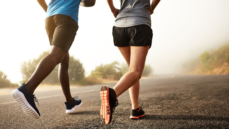 Waist-down photo of two people jogging on tarmac