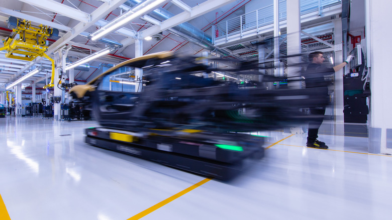 An autonomous cart moves from one station to another on a white factory floor.