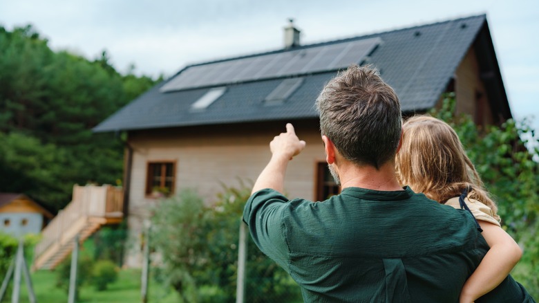 man holding child pointing at solar panels