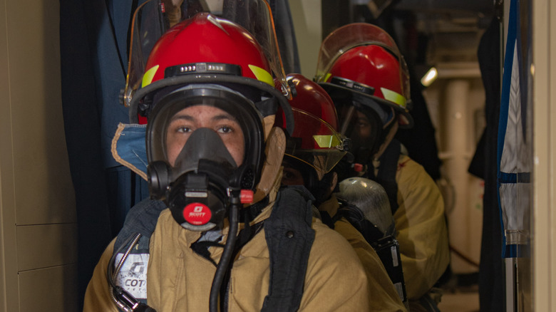 three firefighters lined up in a row, one behind the other