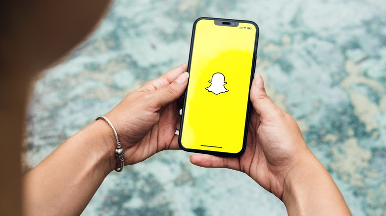 woman holding phone with Snapchat logo on screen