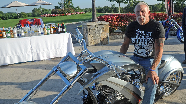 Paul Teutul Sr. in black Orange County Choppers T-shirt sitting on silver custom chopper