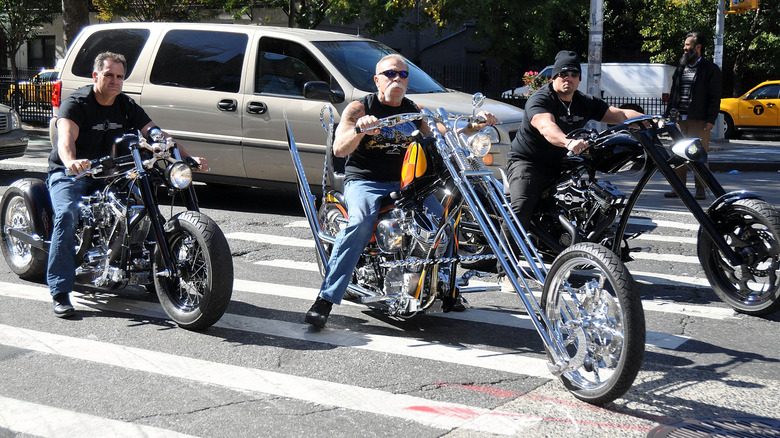 Paul Teutul Sr. riding chopper on sidewalk in between two other bikes