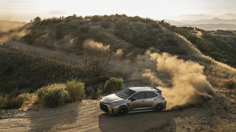 GR Corolla sliding around curve on dirt road, throwing up dust