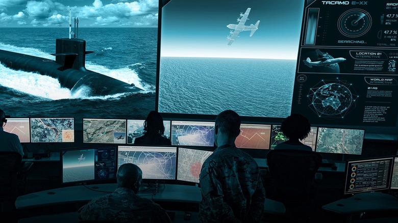 Sailors in a military communications operations center viewing images of submarines, aircraft, and tactical readouts