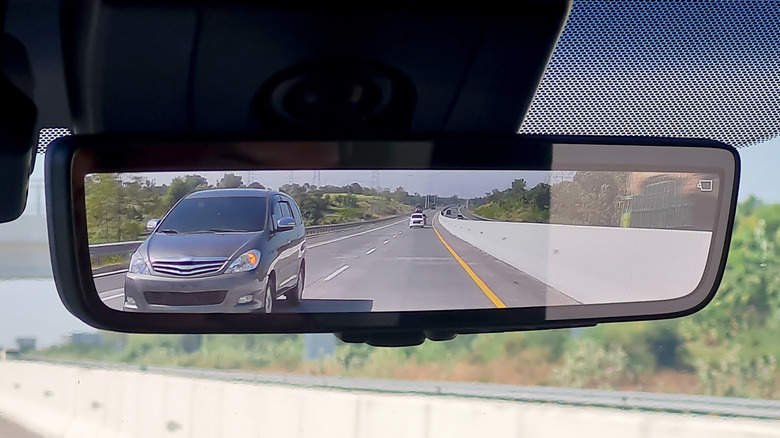 A rear view mirror showing cars in the distance.