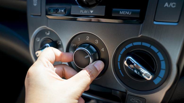 Hand turning on car air conditioning system