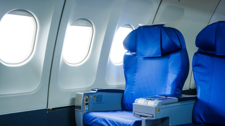 Blue airplane seats next to open windows