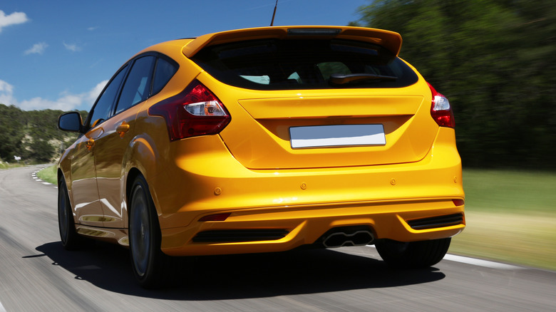 A yellow car driving down the road.