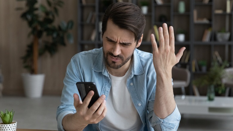 Annoyed man looks at phone