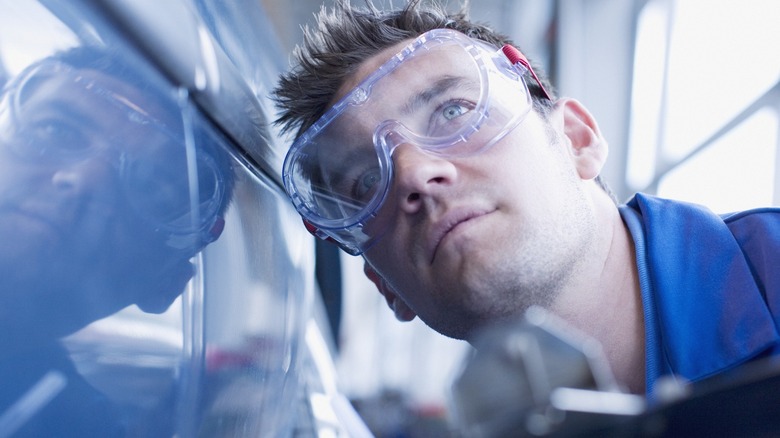 Man wearing goggles inspecting car