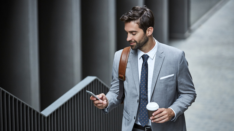 Man with coffee holding phone