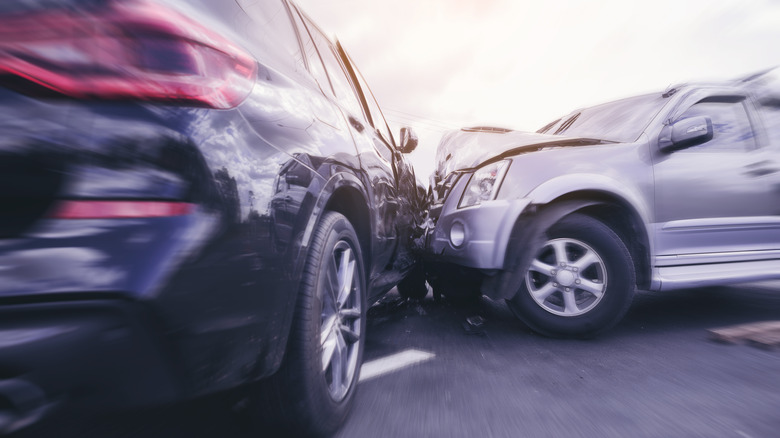 A silver SUV crashing into the side of a black SUV.