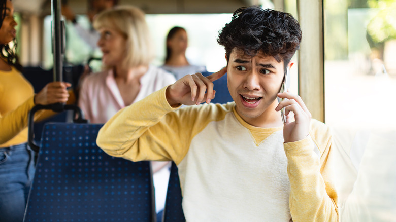 Confused Asian man talking on his phone.