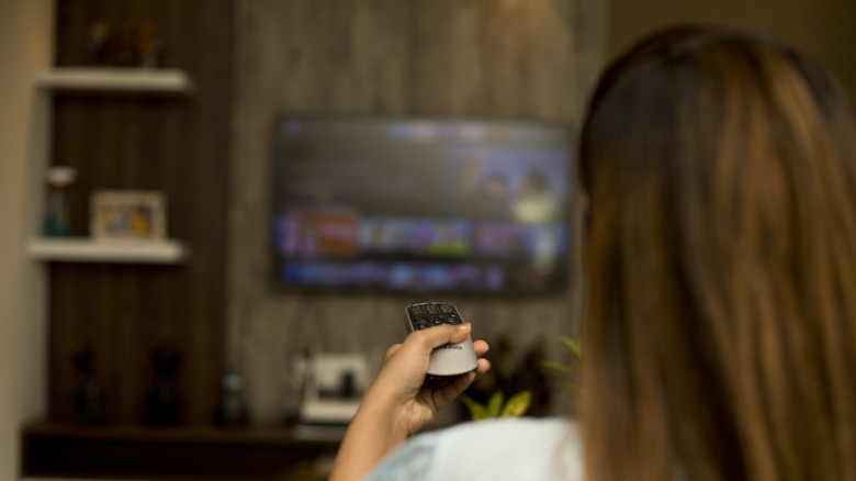 Individual holding a TV remote