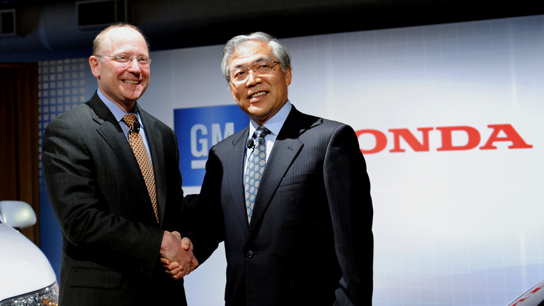 Honda and GM executives shake hands.