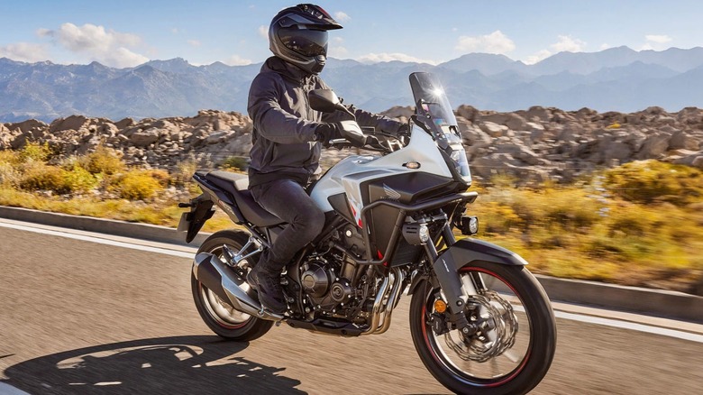 The Honda NX500 Adventure Bike riding past a rocky landscape.