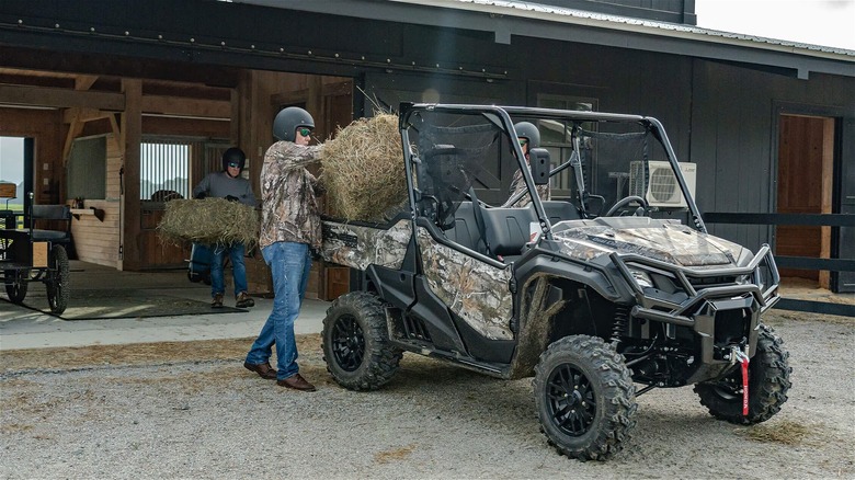 Person loading Pioneer 1000 With Hay Bales