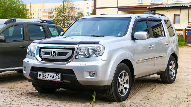 A gray Honda Pilot parked by a house