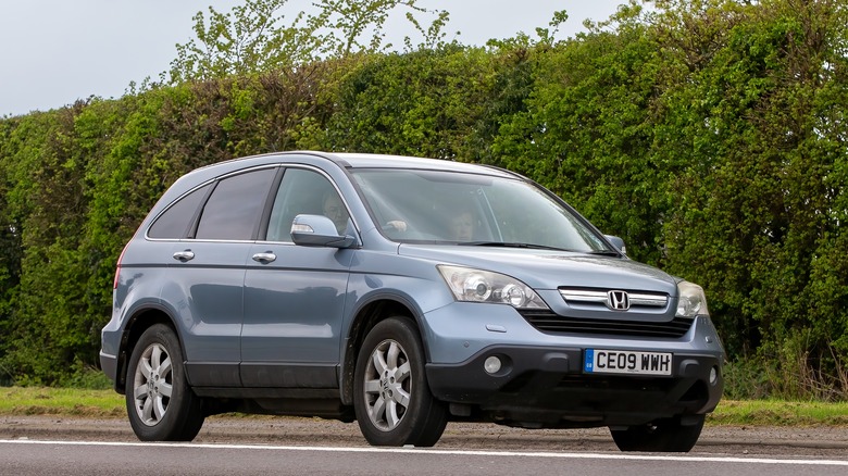 A blue-gray Honda CR-V driving up the road