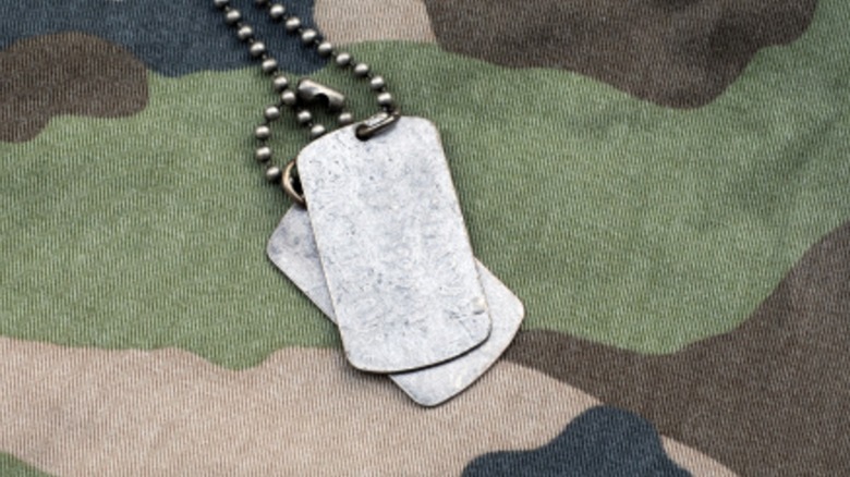 Generic U.S. military dog tags over a camo pattern