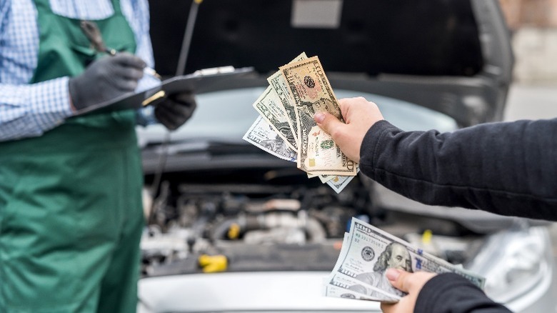 female hands giving dollar notes to mechanic