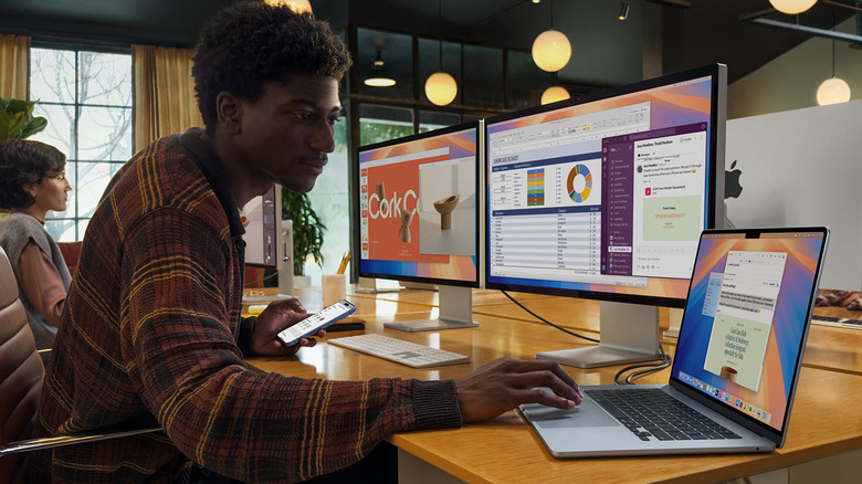 Person using a MacBook Air M4 connected to two external monitors