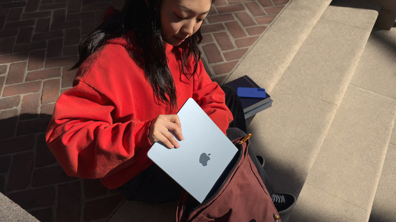 Person putting a MacBook Air in a backpack