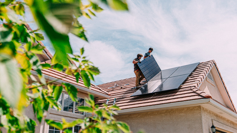 two workers installing solar panels on a roof