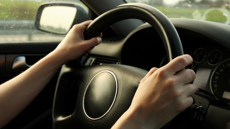 Hands on car steering wheel