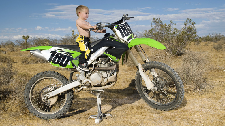 small child standing on dirt bike