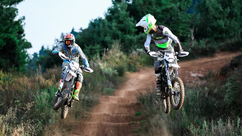 Two Surron e-bikes racing on a trail