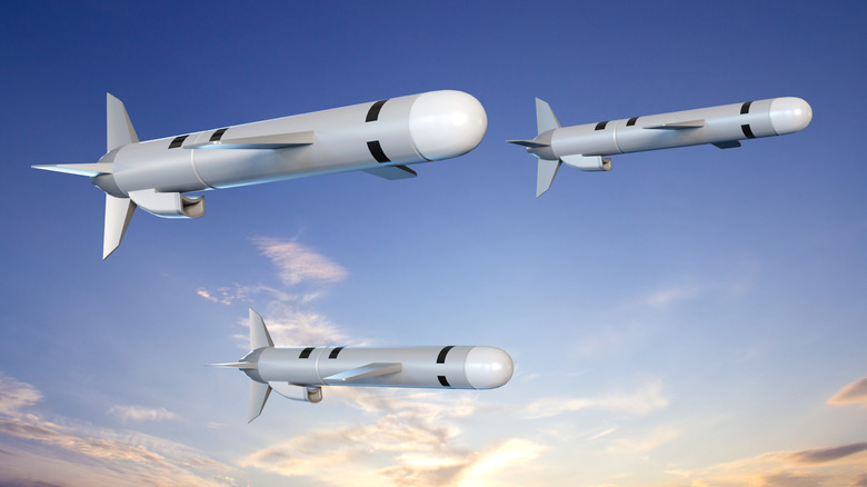 A 3D rendering of three Tomahawk cruise missiles flying before a cloudy sunset