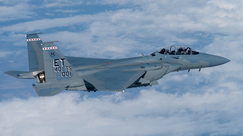 An F-15EX Eagle II flying over sparsely cloudy skies