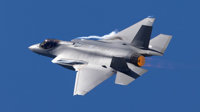 An F-35A Lightning II burning its afterburners over a blue sky