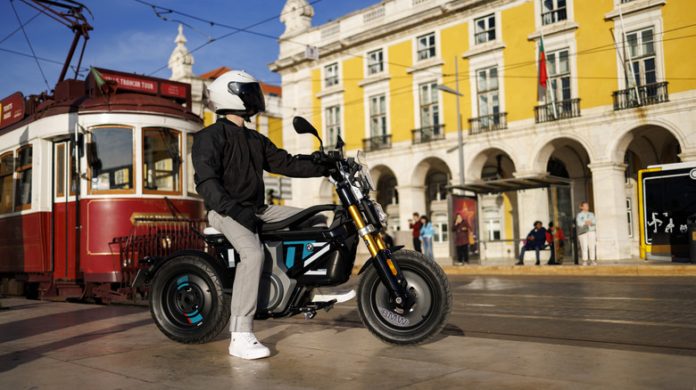 person on BMW CE 02 electric motorcycle on a street with tram in background