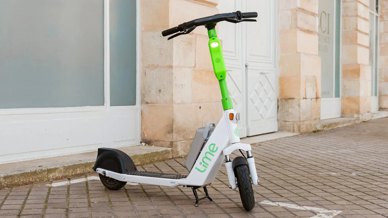 A white and green lime scooter on the street.