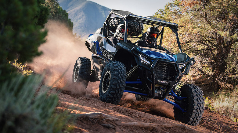 people driving Teryx KRX 1000 on dirt road