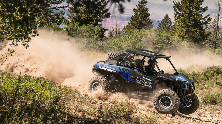 people driving Teryx KRX 1000 on dirt road