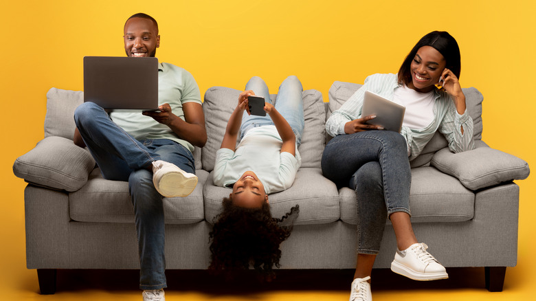 Family using devices on couch