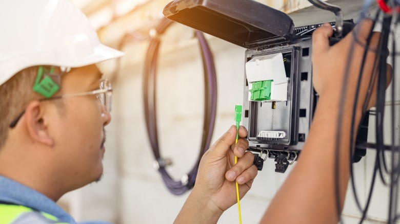 man plugging in fiber optic cables