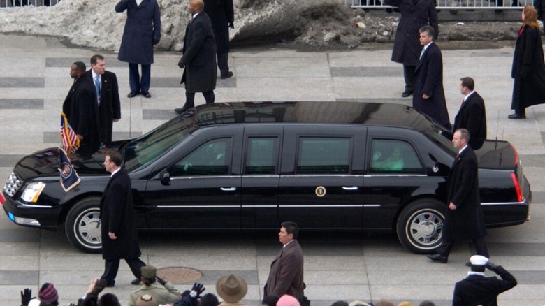 Presidential limo surrounded by onlookers and Secret Service