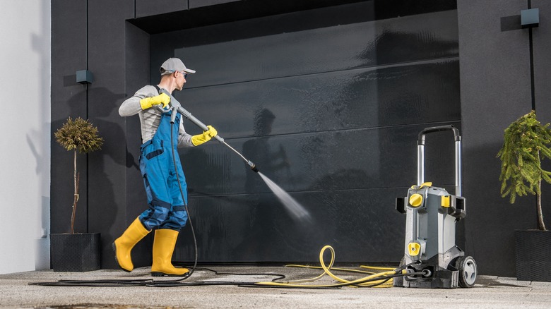 Man pressure washing outside wall 