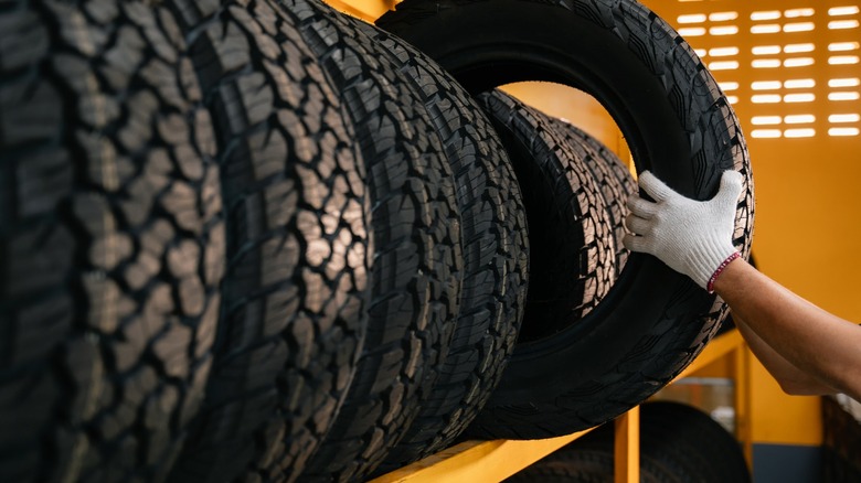 A worker grabbing a new tire off a shelf