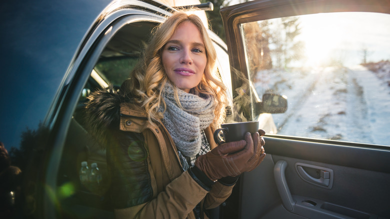 Woman sitting holding coffee in car