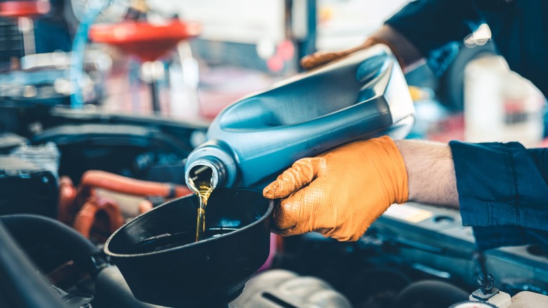 Technician pouring oil into an engine