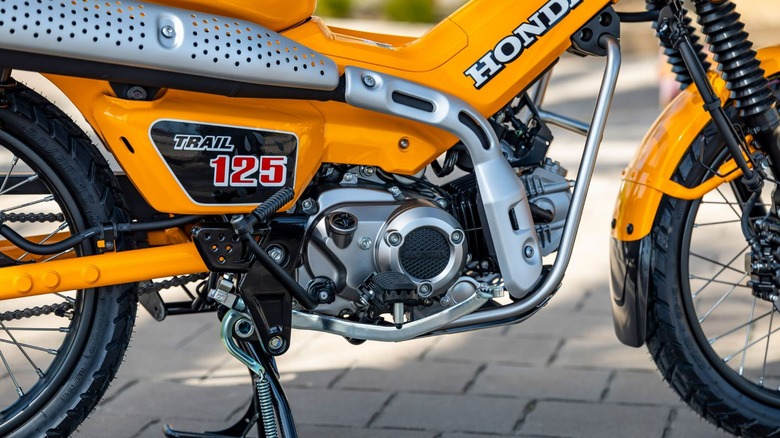 The side of a yellow Honda Trail125.